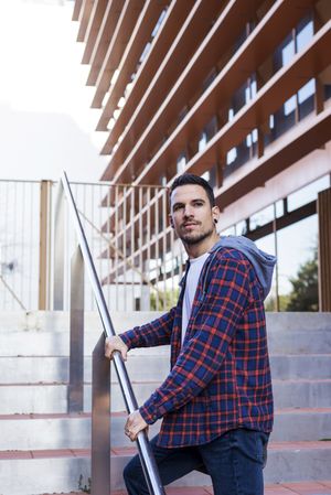 Man in plaid shirt walking up stairs on a sunny day