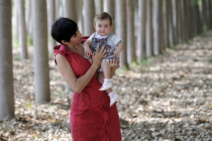 Mother holding cute litle girl in forest
