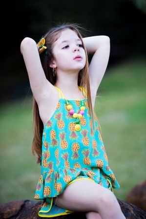 Girl sitting on stone wearing teal and yellow pineapple monogrammed tank dress
