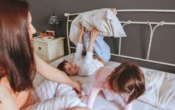 Little boy and girl playing in bed on a relaxed morning with their mother