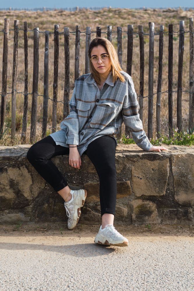 Trendy young female millennial resting on stone border at roadside
