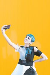 Cheerful futuristic woman taking selfie with smartphone