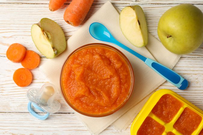 Composition with baby food on plain wooden background