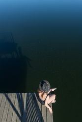 Young female sitting on pier on nature