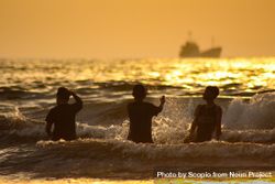 Silhouette of three boys at the beach during sunset 0vAdLb