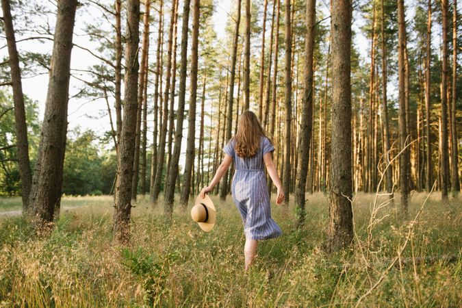 Young woman standing among pine trees