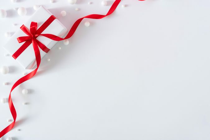Gift box wrapped with red ribbons on light background