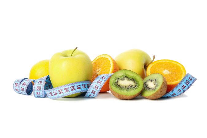 Measuring tape and fruits isolated on light background