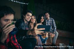 Happy friends taking selfie with a smartphone at party beXroA