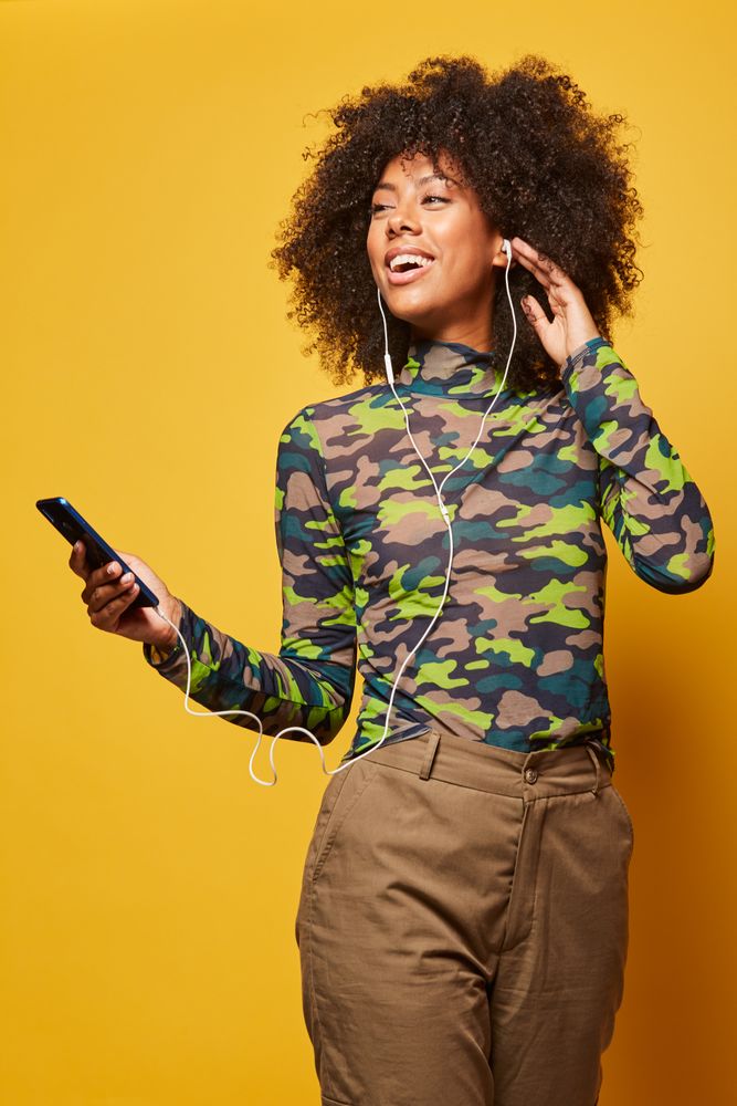 Trendy young Black woman with smartphone listening to music