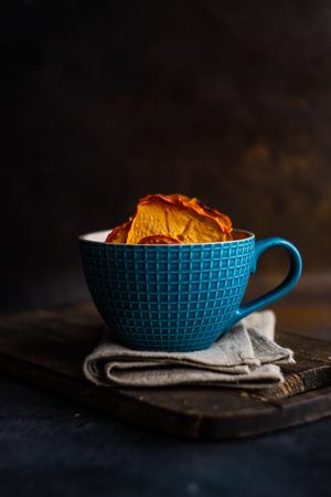 Dried persimmon fruit slices in tea cup with copy space
