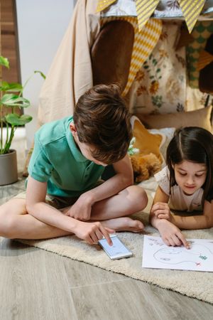 Boy and girl playing treasure hunting game in a tent at home