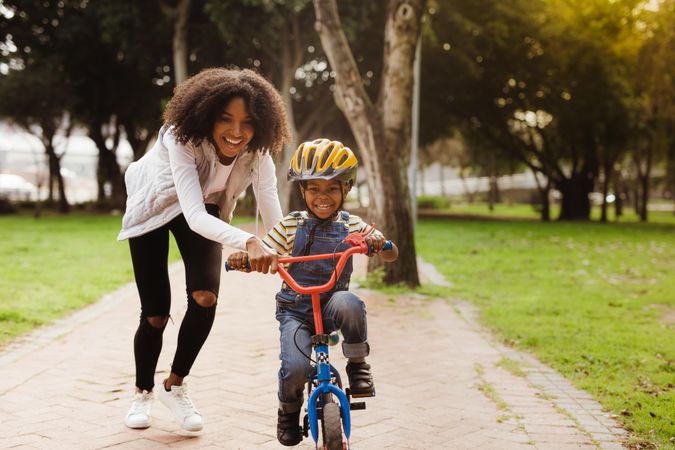 Happy cute boy learn to ride a bike with his mother