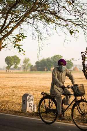 Indian man wearing kurta and turban riding bicycle