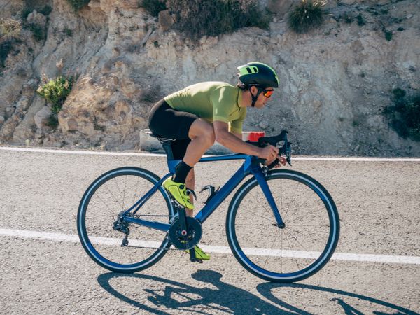 healthy man riding a bicycle on a mountain road in a sunny day