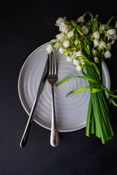 Table setting for Easter dinner with snowdrop flowers on grey plate