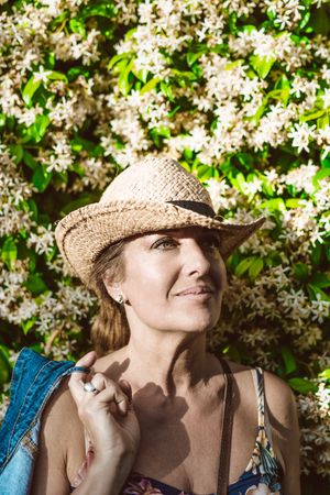 Woman standing near a wall with flower shrubs