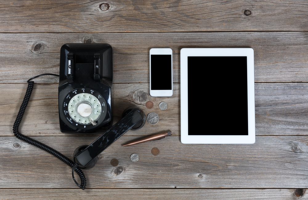 Obsolete and modern communication devices on rustic wood