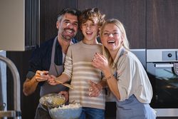 Happy family with faces dirty of dough cooking together at home