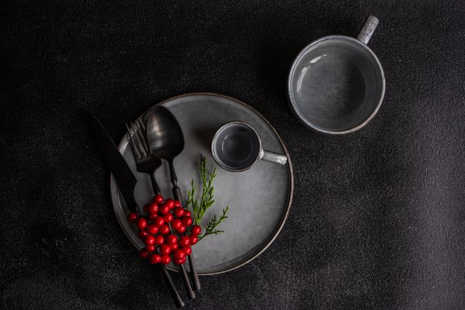 Top view of grey plate and mug surrounded by seasonal red berries