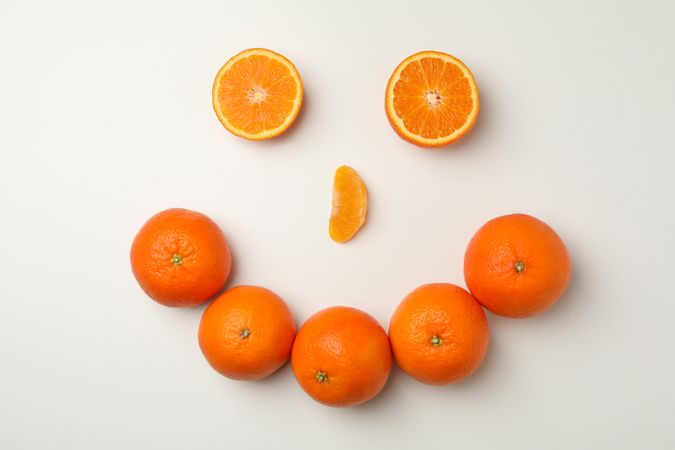 Happy face made of mandarins on light background