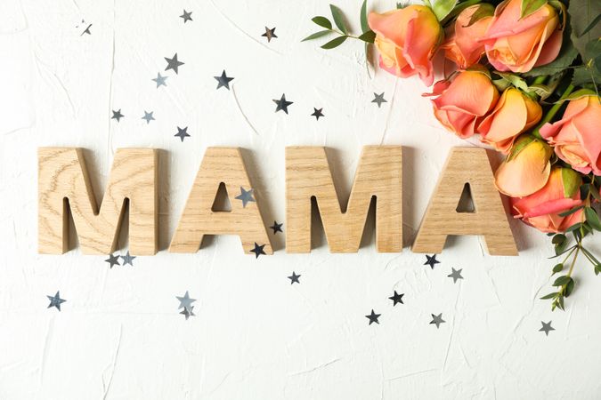 Composition with inscription Mom, pink roses and little stars on light background, top view