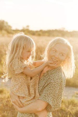 Happy mother and little daughter in field during summer