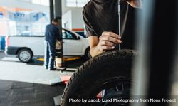 Mechanic checking car tire tread depth with caliber beJkG0