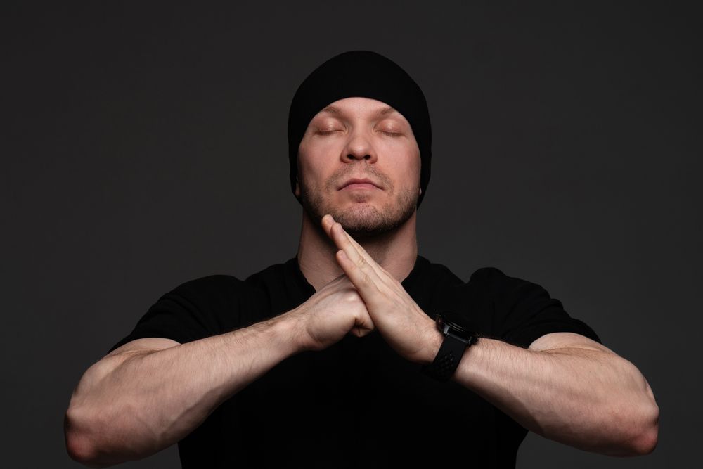 Man in beanie and sweatshirt meditating with hands together