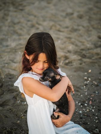 Girl with little dog on sandy beach