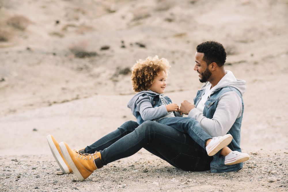 Black father playing with child on ground