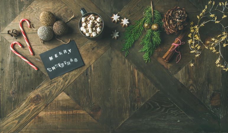 Homely holiday with “Merry Christmas” card, candy canes, pine cones, hot chocolate, copy space