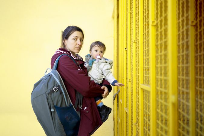 Side view of a woman holding her child in front of yellow wall