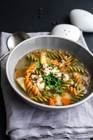 Healthy soup with spinach pasta and meat balls served on the table with copy space