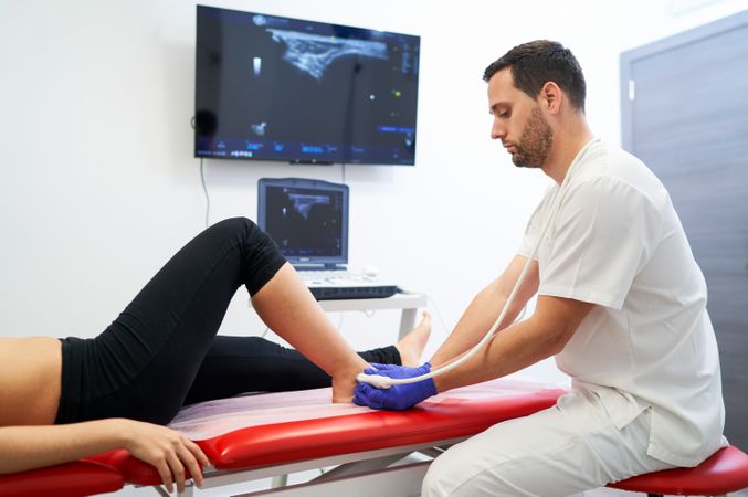 a physiotherapist performing an ultrasound on the ankle to check