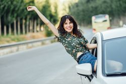 Smiling brunette female waving outside passenger window