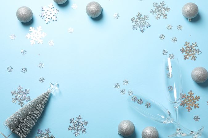 Champagne glasses and christmas baubles on blue background, copy space