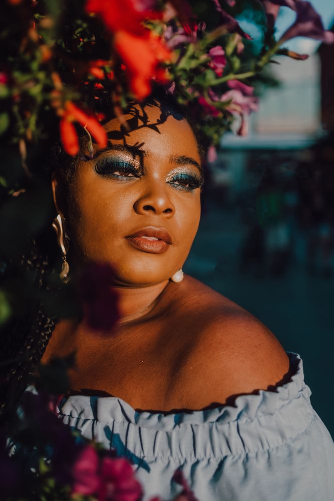 Joyful trendy Black woman standing beside blossomed tree
