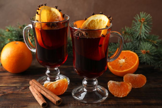 Glasses of tasty mulled wine with orange on wooden background, close up