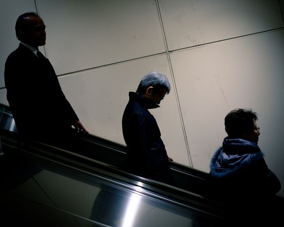 Side view of three men on escalator