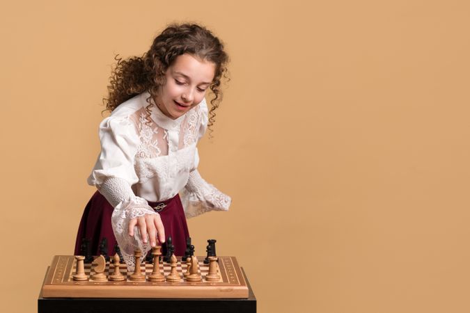 Young girl smiling while adjusting chess pieces