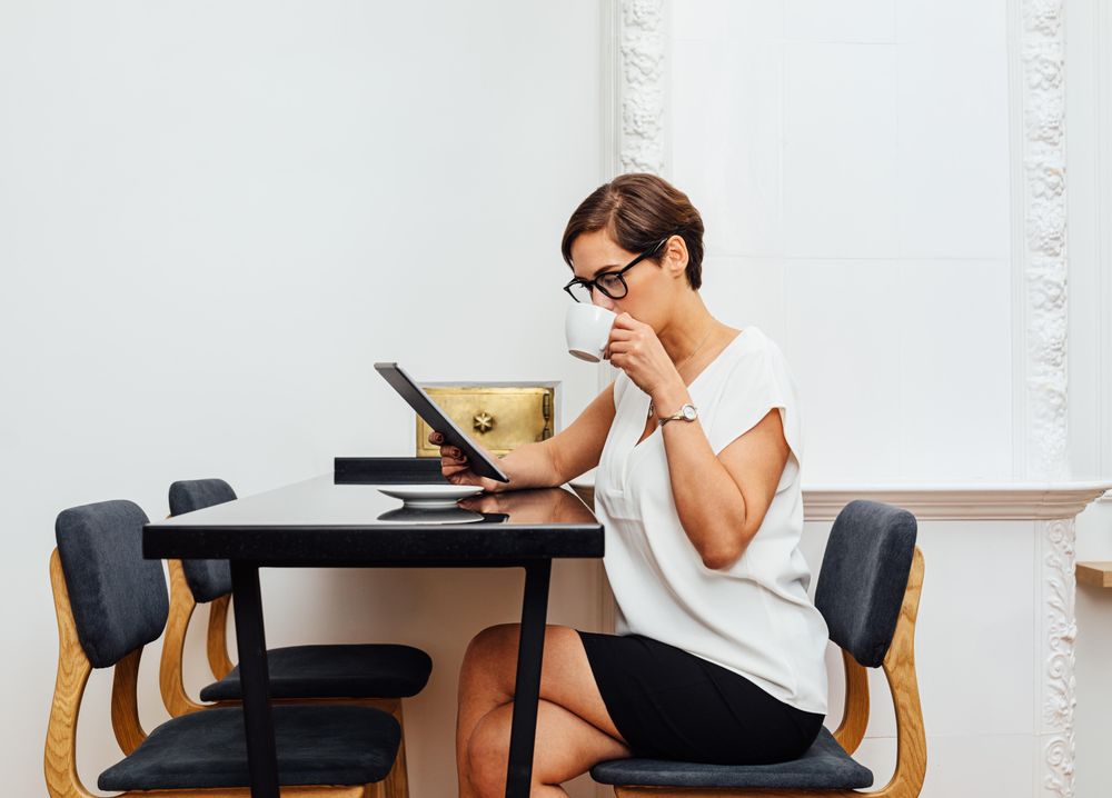 Woman reading on her tablet with a coffee