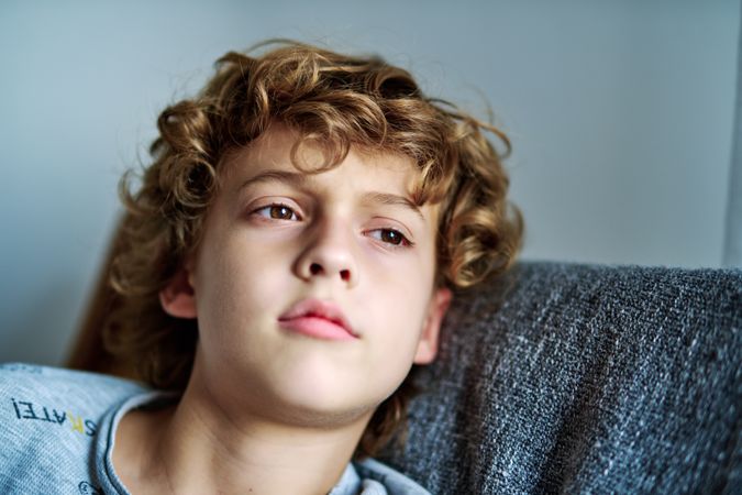 Serene boy with brown eyes lying on sofa