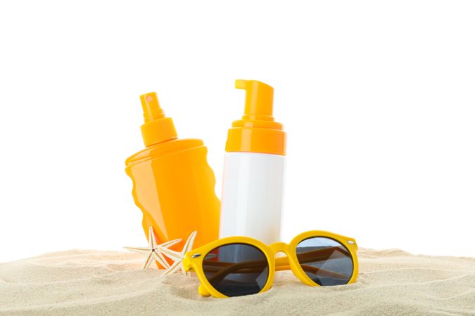 Sunscreens with starfish and sunglasses on clear sea sand isolated on plain background. Summer vacation