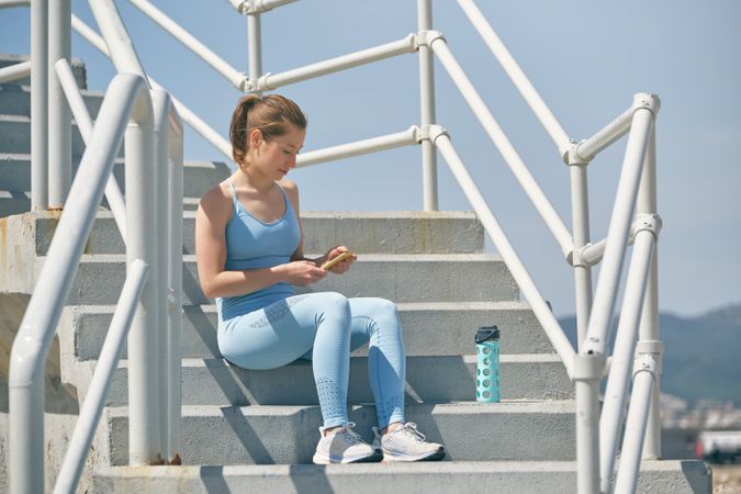 Athlete surfing internet on smartphone on staircase outdoors