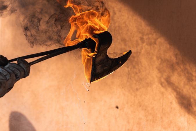 Blacksmith putting hot burning metal viking axe in water