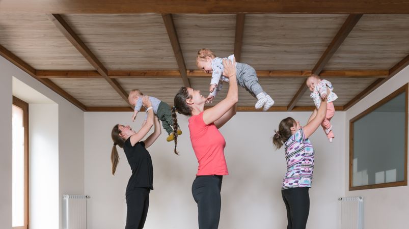 Mothers lifting babies in gym