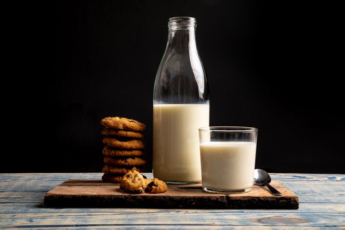 Milk and fresh cookies on board near napkin