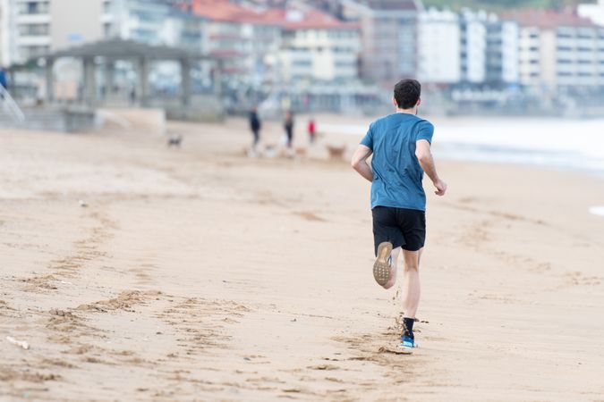 Sportsman in active wear jogging on lonely beach
