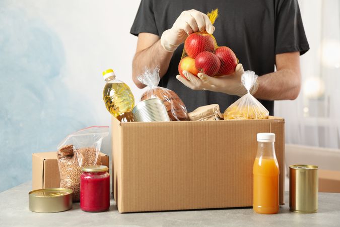 Young man puts groceries in donation box. Volunteer